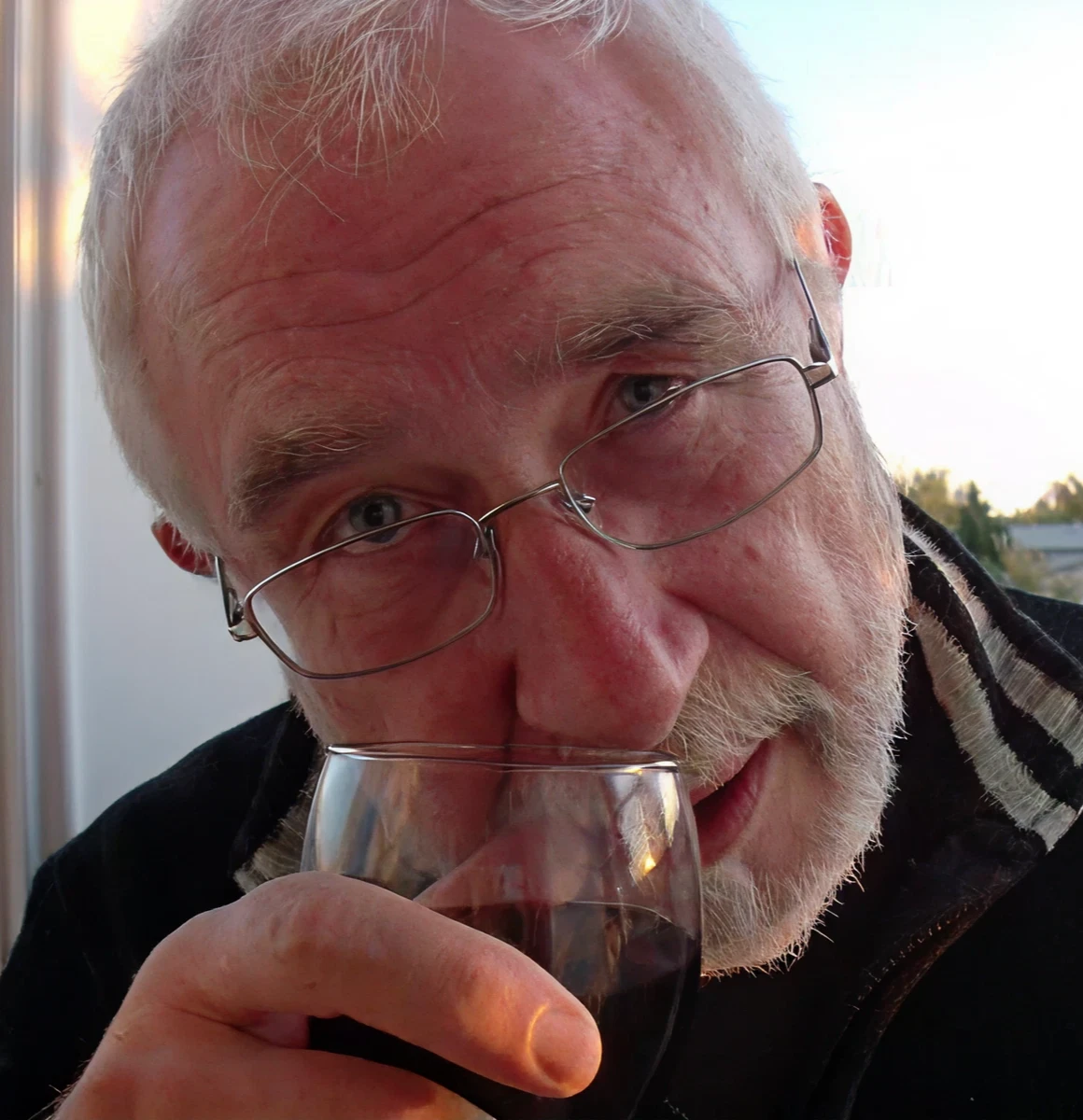 Man drinking wine and looking at camera.