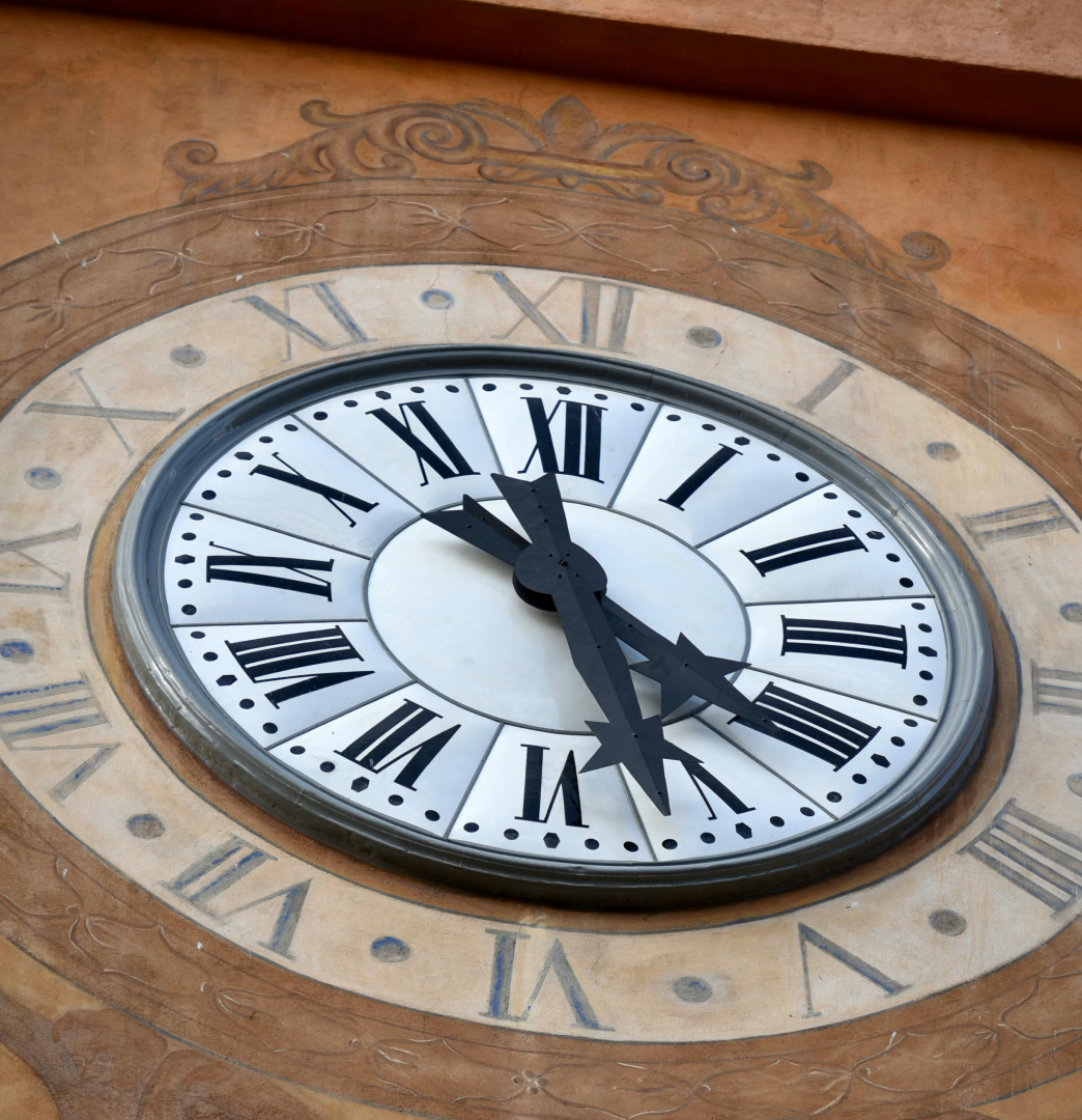 Clock with Roman numerals on building facade.