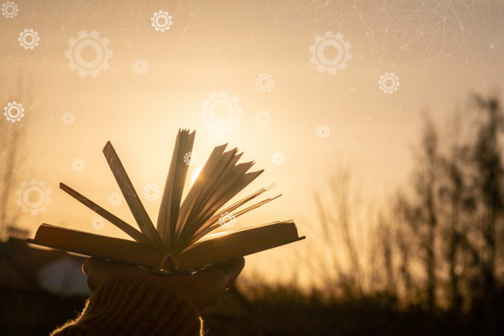 Hand holding open book at golden sunset