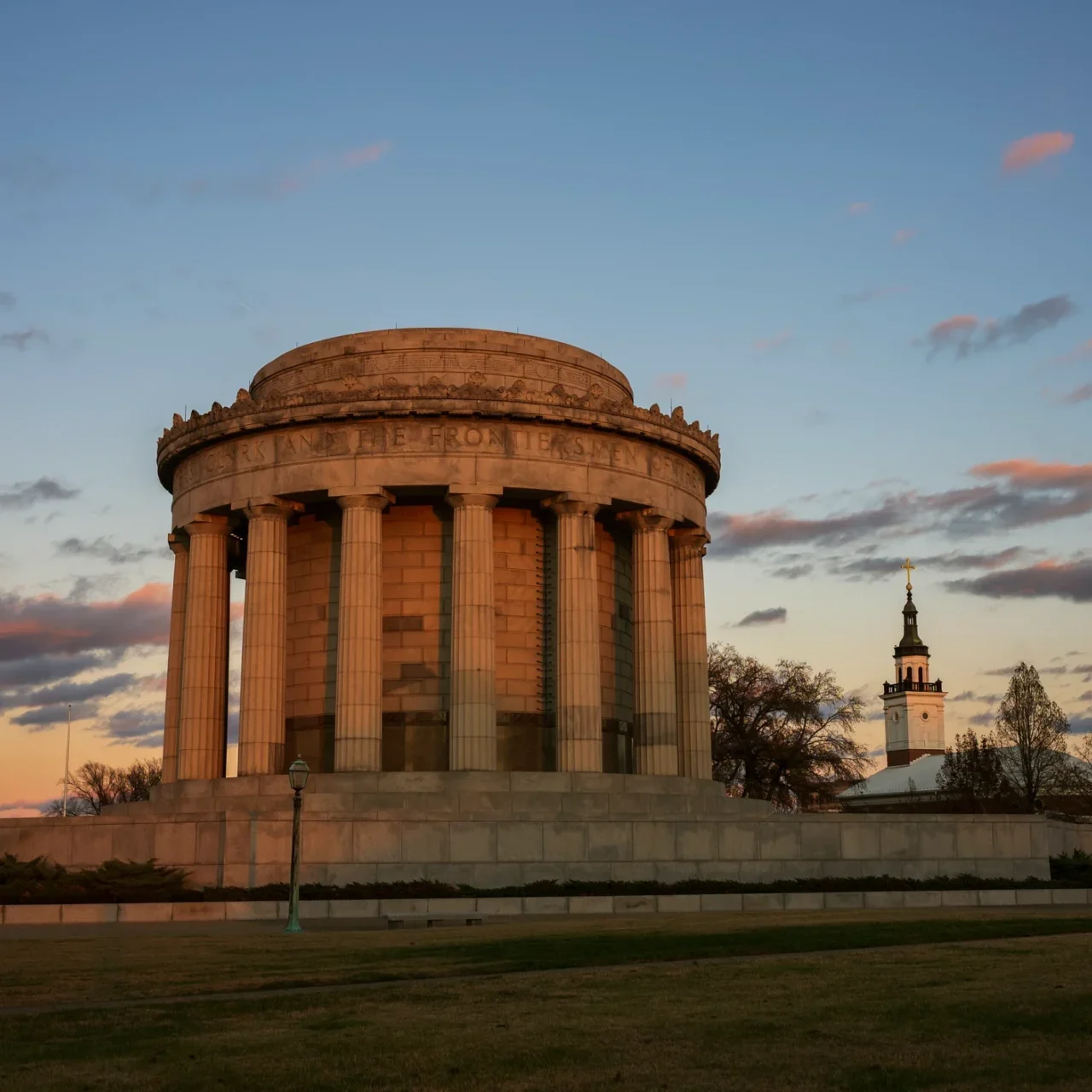 Historic stone monument at sunset, with tower.