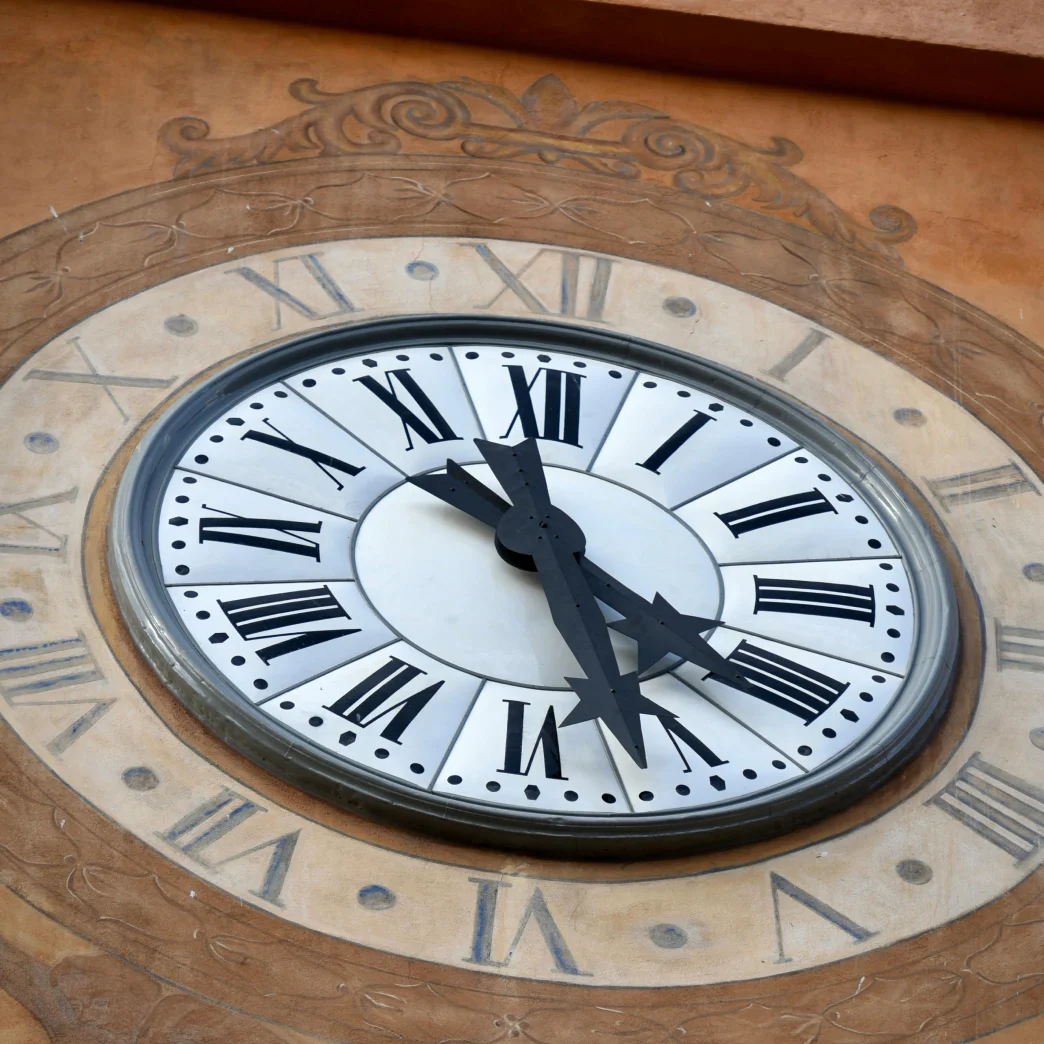 Clock with Roman numerals on building facade.